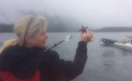 Flori Ens Counsellor at the Lake holding a starfish while smiling
